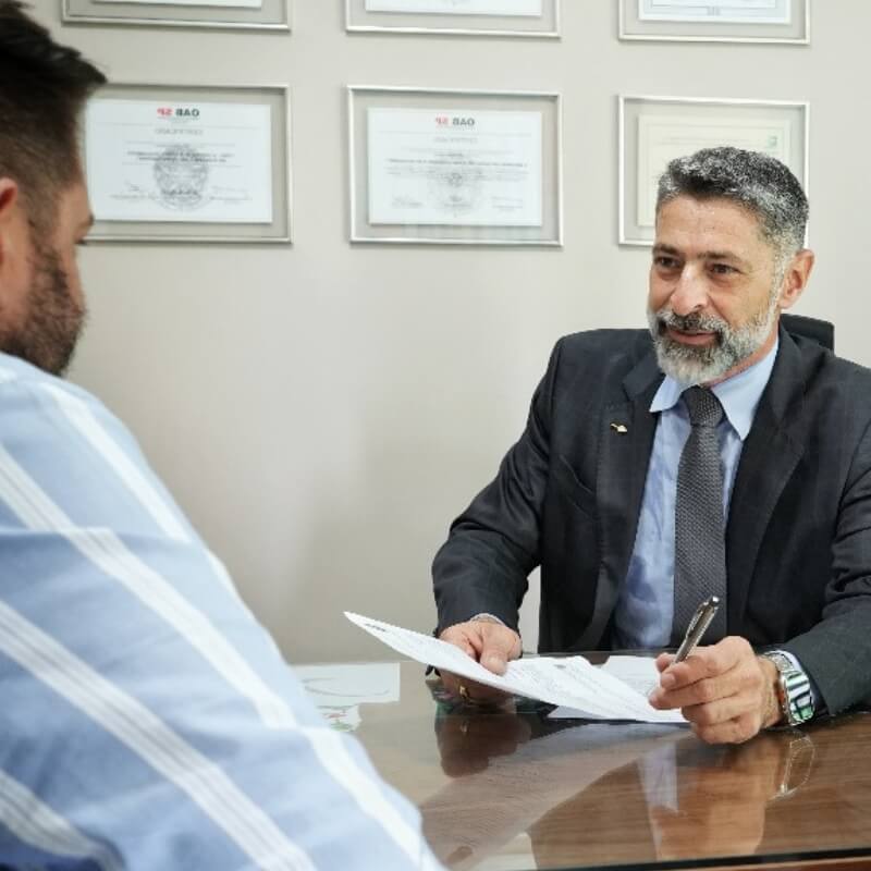 Fotografia mostra o Dr. Fábio sentado à mesa atendendo a uma pessoa