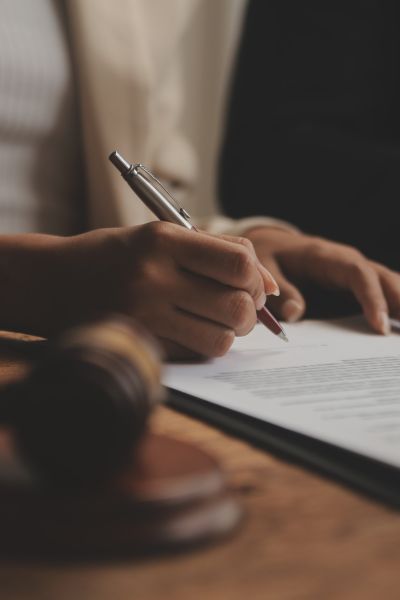 Advogada analisando um documento sobre a mesa, onde se encontra um martelo utilizado por juízes, em tribunais